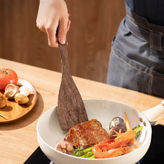 nana retourne viande avec spatule en bois